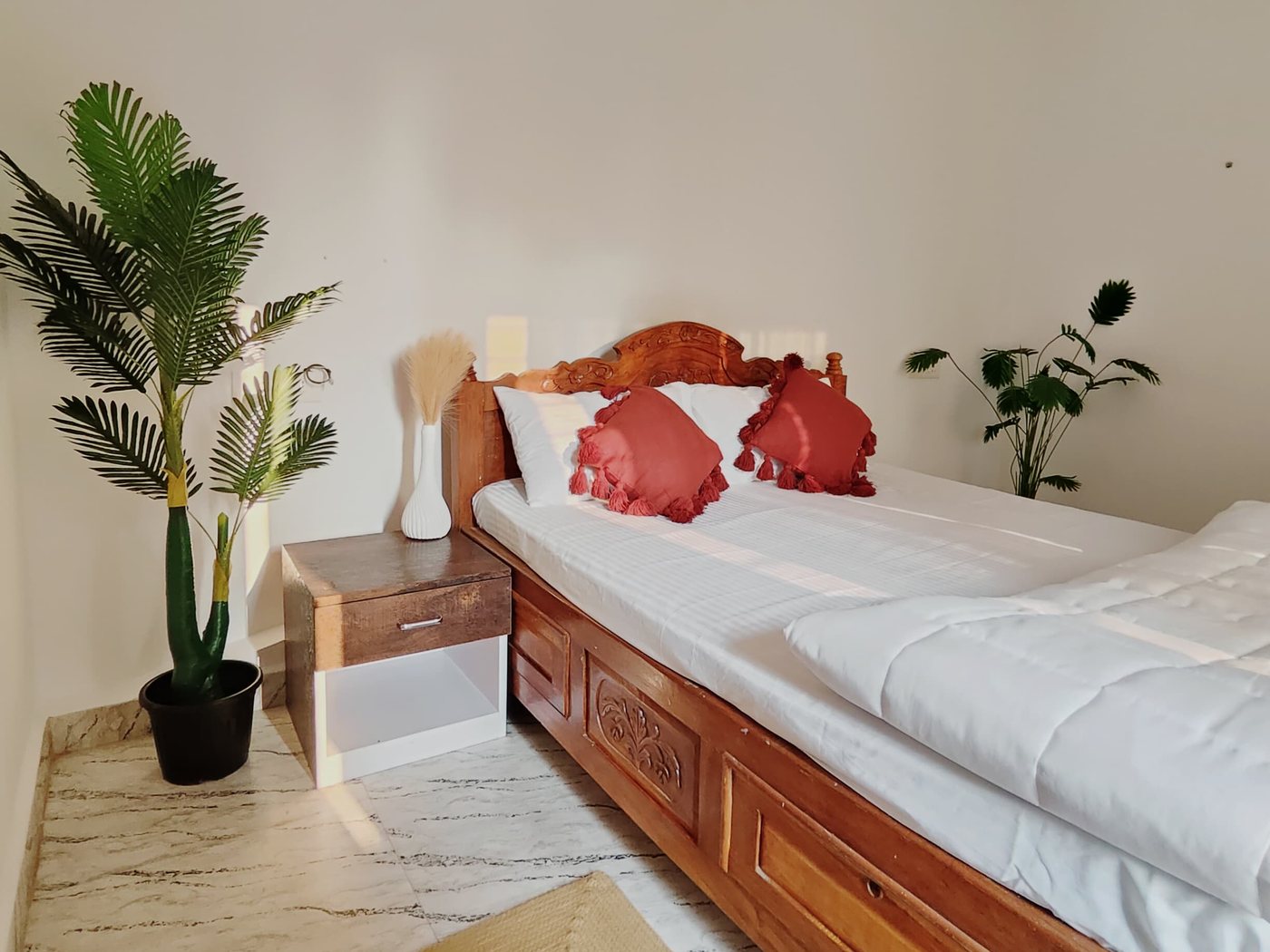 Banyan room: carved bed, red cushions and a palm by the window