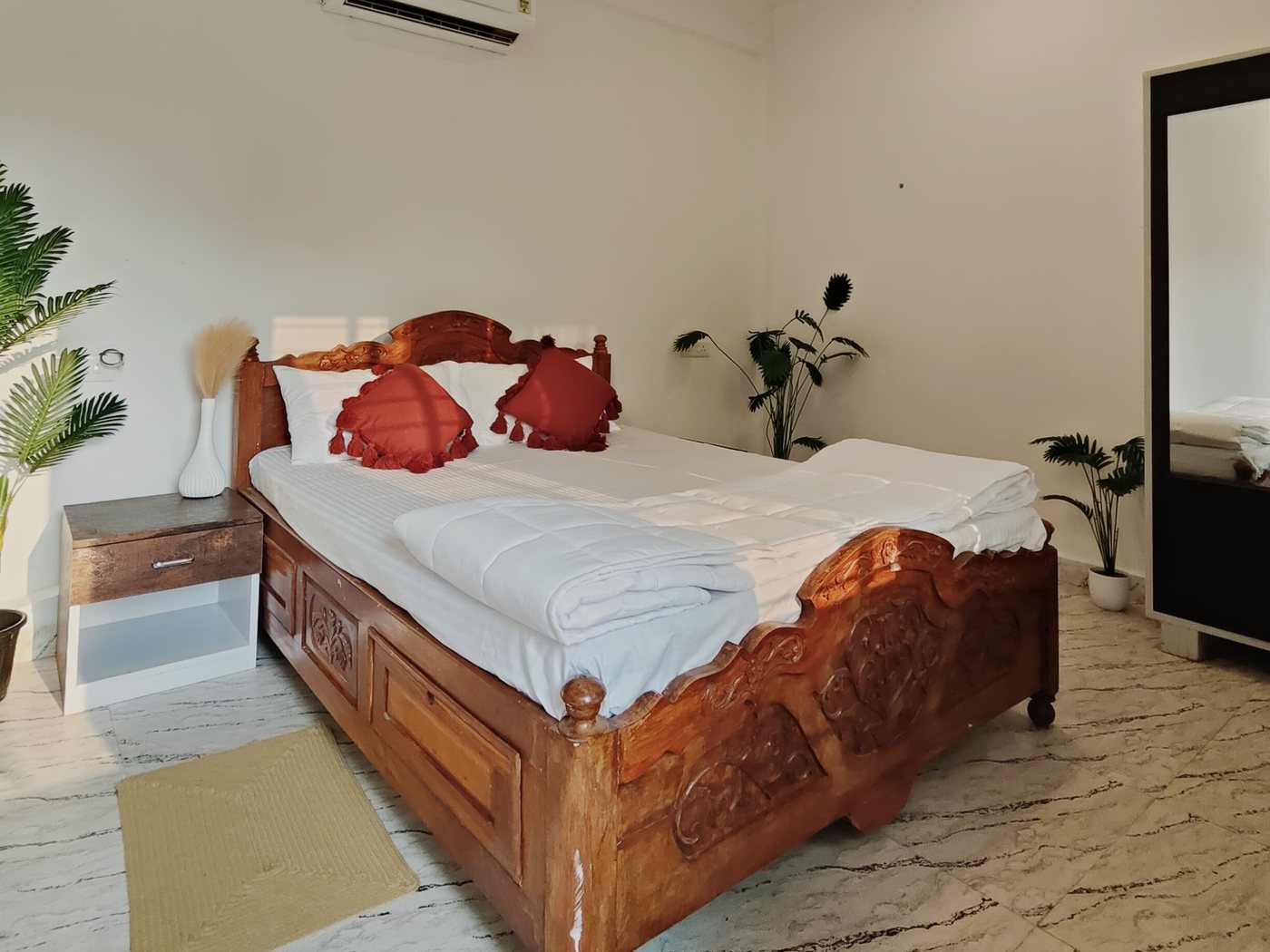Mango room: carved teak bed, mirror wardrobe and plants